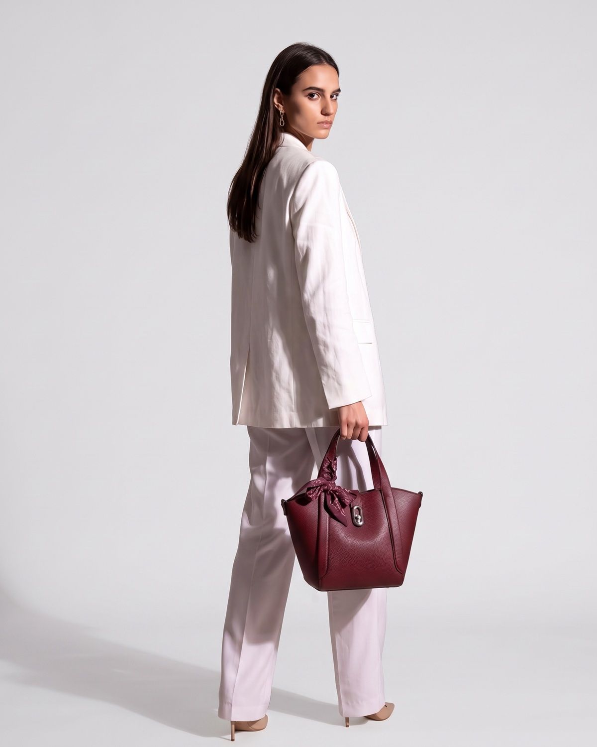 Model standing and looking back over her shoulder while showcasing the Bagco Noelle vegan PU leather tote.